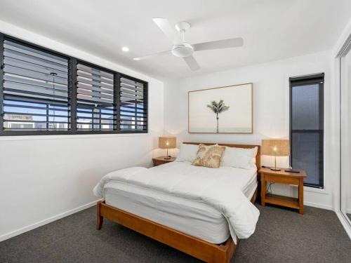 a white bedroom with a bed and two lamps at 1 Bedroom Modern Townhouse in Casuarina in Casuarina