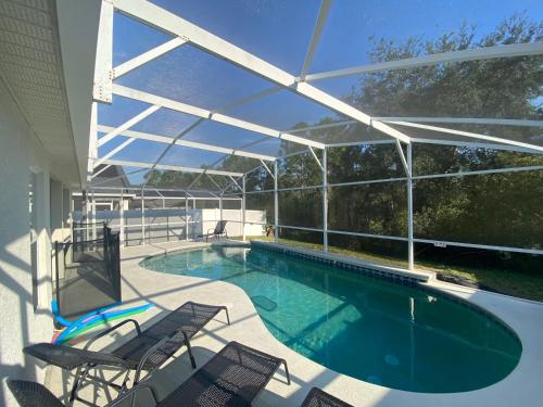 a swimming pool with chairs and a patio with a roof at 3 Bedroom Villa with Poolside Cinema and Games Room Close to theme Parks sleeps 6 plus 2 in Orlando