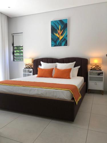Un dormitorio con una cama grande con almohadas naranjas. en Montecrista Appart moderne et cosy, 1 chambre à 2 min plage Pereybere, en Pereybere