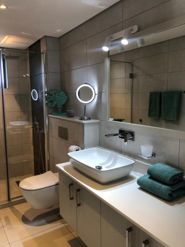 La salle de bains est pourvue d'un lavabo, de toilettes et d'un miroir. dans l'établissement Montecrista Appart moderne et cosy, 1 chambre à 2 min plage Pereybere, à Pereybere