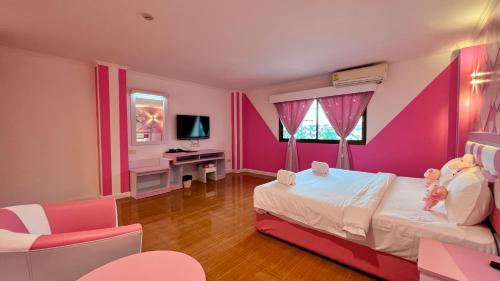 een slaapkamer met roze muren, een bed en een bureau bij The Wai Hotel Danok in Sadao