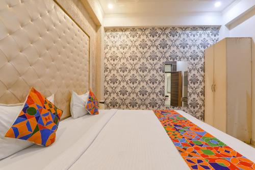 a bedroom with a white bed with colorful pillows at FabHotel Triveni in Jahāngīrābād