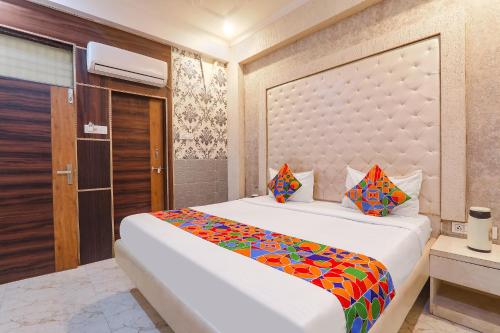 a bedroom with a large white bed with colorful sheets at FabHotel Triveni in Jahāngīrābād