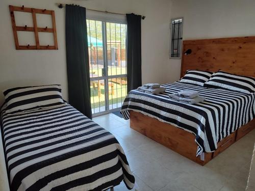 2 camas en una habitación con ventana en Complejo Monaco Calamuchita en Santa Rosa de Calamuchita