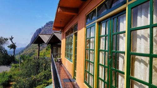 a building with green and yellow windows and a mountain at Green View Ella in Ella