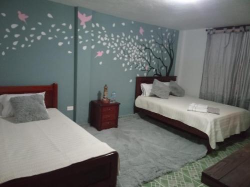 a bedroom with two beds and butterflies on the wall at Quinta Wiñay in Yaruguí