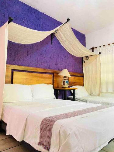 a bedroom with two beds and a purple wall at Casa de Mamá Nico in Barrio Nuevo