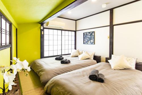 2 łóżka w pokoju z żółtymi ścianami i oknami w obiekcie Vacation rental Miyabi/downtown/Tokyo airport w Tokio