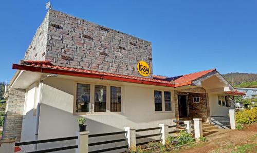 Una pequeña casa blanca con un cartel. en Itsy By Treebo - Twin Falls en Ooty