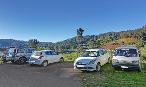 a group of three cars parked on a dirt road at Itsy Hotels Twin Falls in Ooty