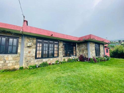 a brick house with a green lawn in front of it at Misty Mountain Lodge Ohiya in Ohiya