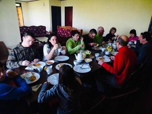 a group of people sitting around a table eating food at Misty Mountain Lodge Ohiya in Ohiya