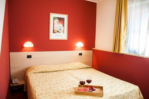 a bedroom with a bed with two glasses of wine at Lizard Hotel in Como