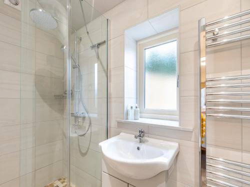 a white bathroom with a sink and a shower at The New Stables in Melbourne