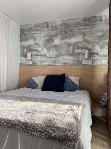 une chambre avec un grand lit avec une tête de lit en bois dans l'établissement Charming ecolodge with heated pool in Charente-Maritime, aux Mathes