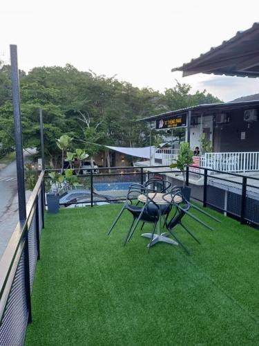 a balcony with a table and chairs on the grass at Tc theme park Guest house in Kuantan