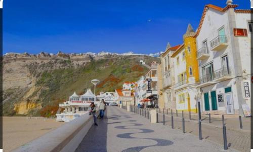 um grupo de pessoas andando por uma rua ao lado de edifícios em Estúdio dos bonés em Nazaré