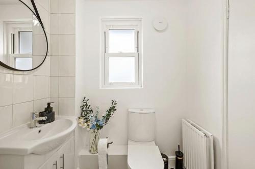 Baño blanco con aseo y lavamanos en 5 guests 3 beds 1 sofa bed Lewisham en Londres