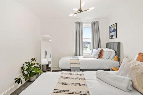Habitación blanca con 2 camas y espejo. en 5 guests 3 beds 1 sofa bed Lewisham, en Londres