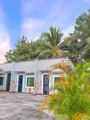 ein weißes Gebäude mit Palmen davor in der Unterkunft Sonnylyn Guest House in Siquijor