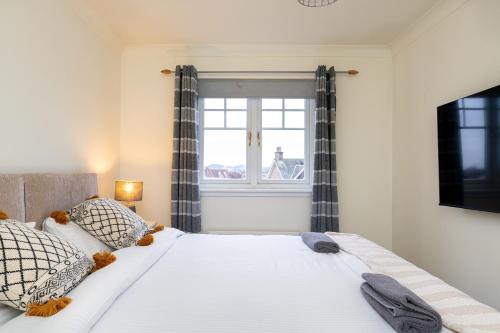 a bedroom with a large white bed with a window at 4 Bedroom Townhouse in Stirling in Stirling