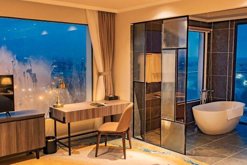 a bathroom with a tub and a desk and a sink at La Vela Hue Hotel in Hue