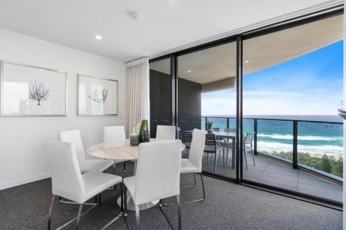 a dining room with white chairs and a table with a view at Oracle Resort Broadbeach - gclr in Gold Coast