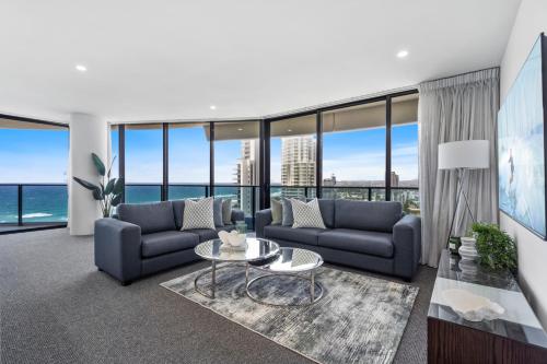a living room with blue couches and a table at Oracle Resort Broadbeach - gclr in Gold Coast