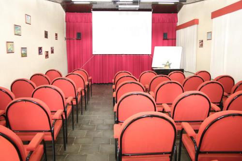 a lecture hall with red chairs and a screen at Pousada Ribeirão do Ouro in Itamonte