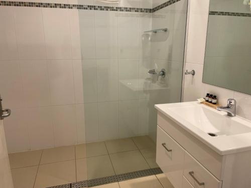 a white bathroom with a shower and a sink at Millthorpe Motel in Millthorpe