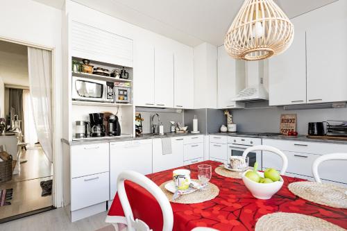 una cucina con armadi bianchi e tavolo e sedie rossi di Casa Merikotilo merellisessä Meriraumassa. a Rauma