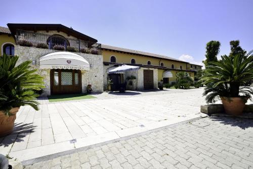 a building with a courtyard with palm trees in front of it at Hotel Tenuta San Francesco in Barletta