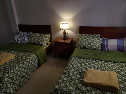 ein Schlafzimmer mit 2 Betten und einer Lampe auf einem Nachttisch in der Unterkunft JLF Inn in Locsin