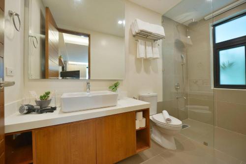 a bathroom with a sink and a toilet and a mirror at The Apartments at El Nido in El Nido