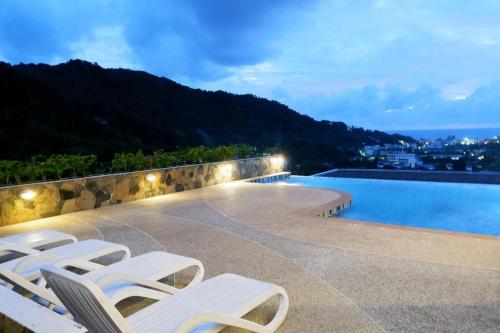 a group of white lounge chairs next to a swimming pool at Kata Ocean View Condominium, Seaview & Luxury K12 in Ban Kata