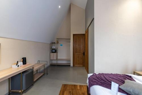 a room with a bed and a desk and a kitchen at Tanaga CoLiving in Seminyak