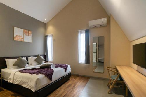 a hotel room with a bed and a television at Tanaga CoLiving in Seminyak