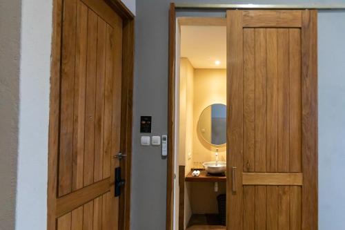 a bathroom with a wooden door and a sink at Tanaga CoLiving in Seminyak