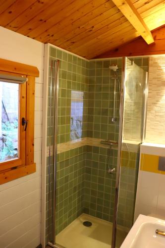 y baño con ducha de azulejos verdes y lavabo. en Casa Del Torrente en Porto Ota