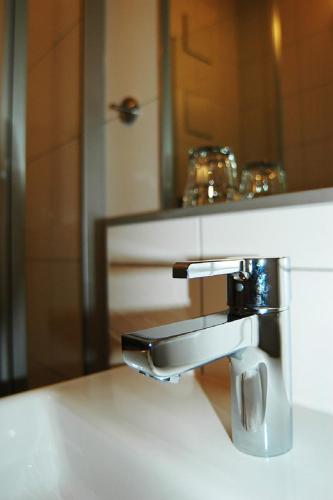 a bathroom sink with a faucet in front of a mirror at Hotel Fränkischer Hof in Buxheim