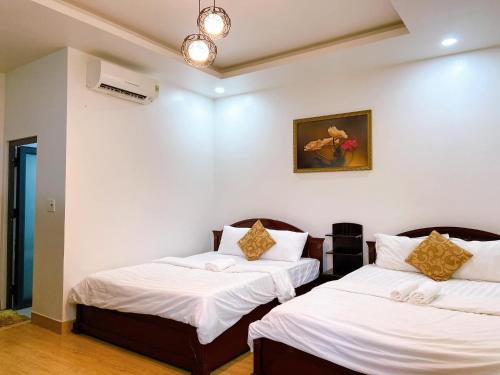 two beds in a room with white walls at Hoàng Lộc Phát Hotel in Cái Răng