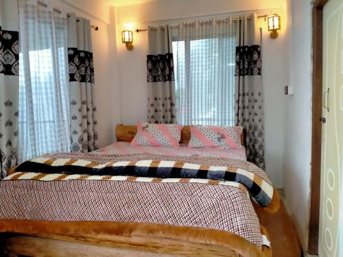 a bedroom with a bed with pink and black sheets at Ajit Homestay, Darjeeling in Darjeeling