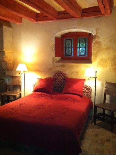 - une chambre avec un lit doté de draps rouges et une fenêtre dans l'établissement Château de Saint Loup, à Saint-Loup-Lamairé