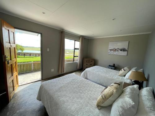 a bedroom with two beds and a large window at Holbank River Lodge in Ermelo