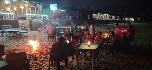 a group of people sitting around fires at night at Saxony Village Resort in Agonda