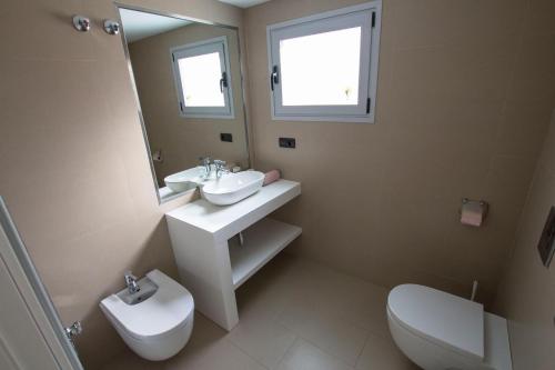 ein Badezimmer mit einem Waschbecken, einem WC und einem Spiegel in der Unterkunft Moderno y bonito apartamento en primera linea de playa de poniente in Benidorm