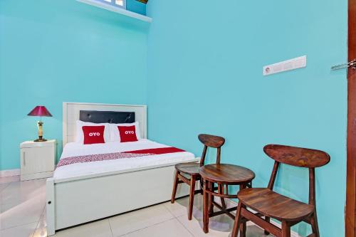 a bedroom with a bed and two chairs in a room at OYO 92294 Amole Homestay Syariah in Cilacap