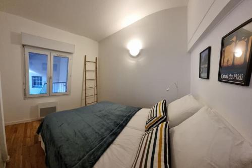 um pequeno quarto com uma cama e uma janela em T2 Charmant - Hypercentre - Quai de Garonne - Wifi em Toulouse