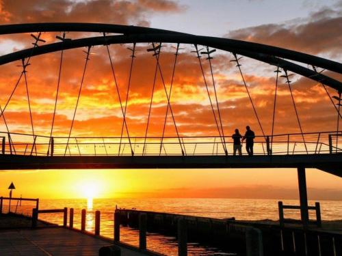 two people standing on a bridge over the ocean at sunset at Sandy Shores Estate- Long Island in Frankston