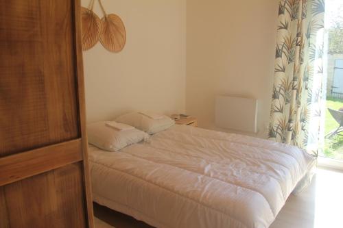 een slaapkamer met een bed met witte lakens en een raam bij le clos des chevaliers in Pons